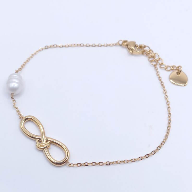 Βραχιόλι χεριού ατσάλινο, χρυσού χρώματος, σε αλυσίδα μήκους 19 cm, η οποία συγκρατεί στοιχείο με συμβολισμό το άπειρο μήκους 2 cm και λευκό μαργαριτάρι.